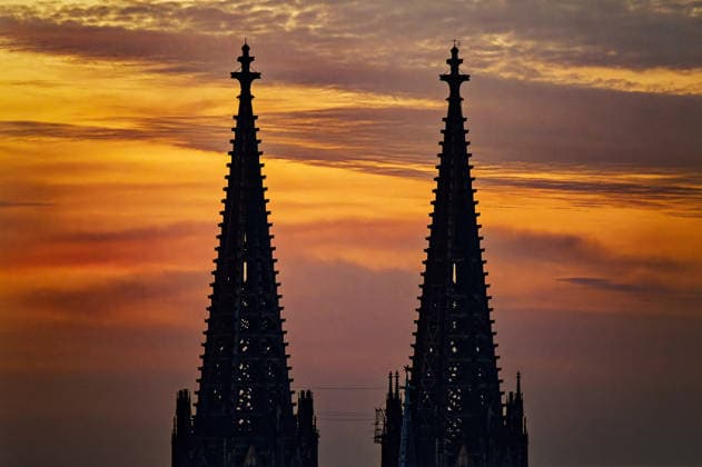 Atmosphärische Silhouette der berühmten Turmspitzen ds Kölner Doms vor einem dramatischen, orange-violetten Sonnenuntergangshimmel in Deutschland *** atmospheric Silhouette the famous Tower spires DS Cologne Doms before a dramatic, Orange purple Sunset sky in Germany 1133501902