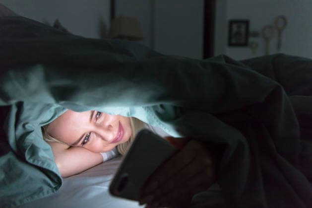Frau liegt nachts im Bett unter einer Decke und benutzt ihr Smartphone. Schlaflosigkeit, Melatonin, Internetabhängigkeit Cheerful relaxed woman lying in bed under the blanket using mobile phone at late night, can not sleep. Insomnia, nomophobia, internet addiction concept. Smartphone, social network addiction (License=RF) ,model released, Symbolfoto Copyright: xZoonar.com DmitriixMarchenkox xEnvatox 24688708 ,model released, Symbolfoto ,property released