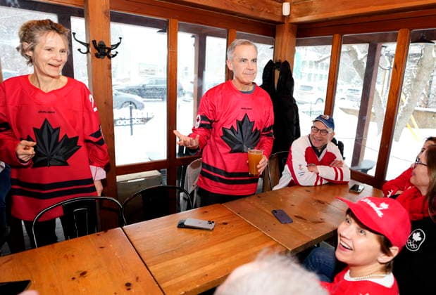 February 22, 2026, Chelsea, Pq, CAN: Prime Minister Mark Carney, centre, and his wife Diana Fox Carney get ready to watch the gold medal men s ice hockey game between Canada and the United States at the 2026 Milan Cortina Winter Olympics, at a pub in Chelsea, Que., on Sunday, Feb. 22, 2026. Chelsea CAN  - ZUMAc35_ 20260222_zaf_c35_050 Copyright: xJustinxTangx