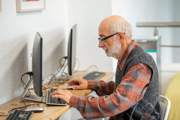 Senior man working on computer at desk. Focused senior man working on computer at desk. model released