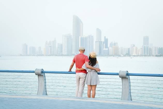 Das kaukasische romantische Touristenpaar steht zusammen und genießt das Skyline Panorama auf einem malerischen Aussichtspunkt in Abu Dhabi. Besuchen Sie das Konzept der VAE, Reisen und Besich Caucasian tourist romantic couple stand together enjoy skyline panorama on scenic viewpoint in Abu dhabi. Visit travel sightseeing UAE concept Copyright: imageBROKER EvaldasxMikoliunas ibxemi16698970.jpg ,model released, Symbolfoto ,property released