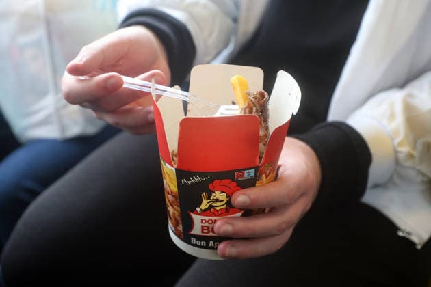 IMAGO Creative, Food, Fast Food, Döner Fast Food unterwegs Eine Pappverpackung, die in Teilen mit Kunststoff versehen ist, befindet sich ein sogenanntes Pommdöner für den schnellen Verzehr. *** Fast food on the go A cardboard package, parts of which are made of plastic, contains a so-called Pommdöner for quick consumption