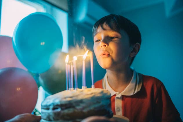 Child blowing out candles on birthday cake with balloons indoors model released, Symbolfoto property released, ANAF05532