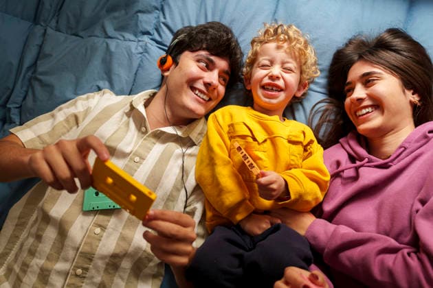 Family laughing together while enjoying retro music cassette indoors model released, Symbolfoto, JZF00166