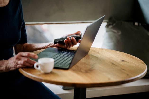 Person using laptop and smartphone at cafÃ table with coffee model released, Symbolfoto property released, KNSF12169
