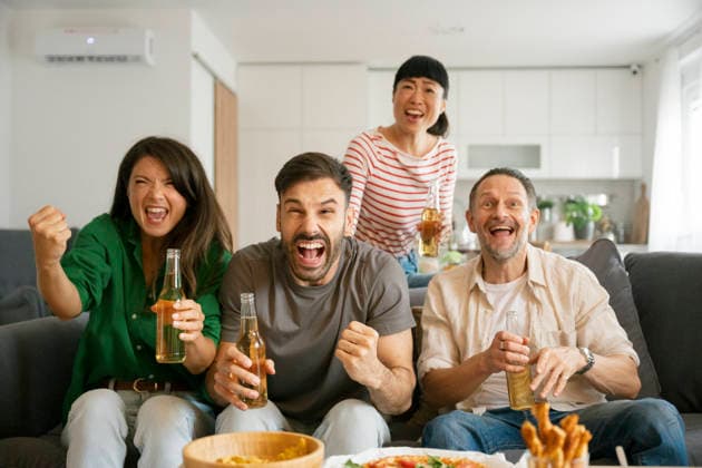 Friends cheering while watching football match at home with drinks model released, Symbolfoto property released, FLMZF02584