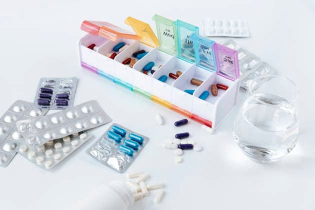 Pill box with assorted medication supplements and water glass, HDF00260