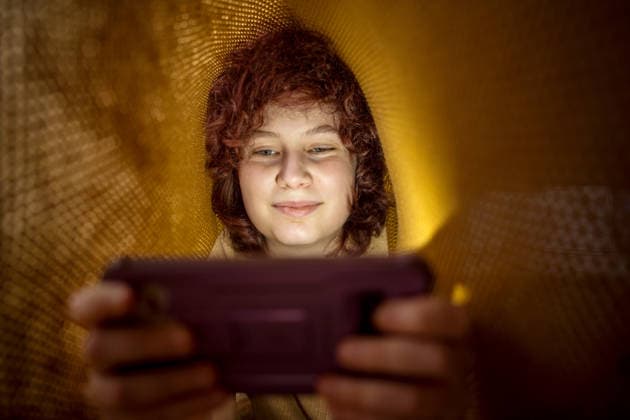 Teenage girl relaxing under blanket and using smartphone in the evening model released, Symbolfoto property released, IGEF00704