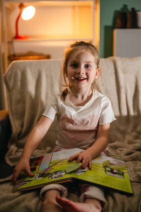 Child reading a book at home at night sitting on a cozy sofa model released, Symbolfoto property released, IGEF00708