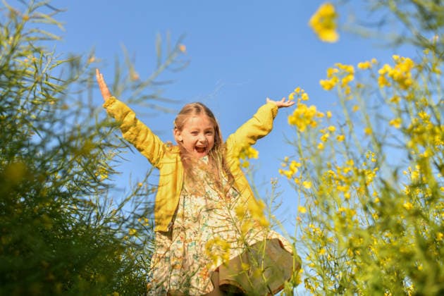 Child in yellow dress smiling joyfully in blooming rapeseed field model released, Symbolfoto, ILF00034