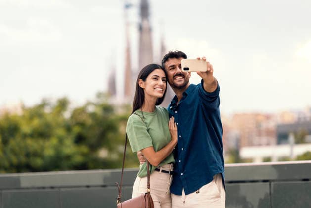 Smiling couple taking a selfie with city architecture in the background model released, Symbolfoto, JSRF04352