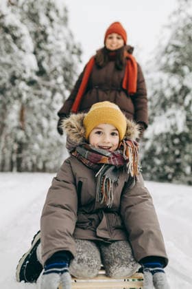 Smiling child sledding with parent in snowy winter forest model released, Symbolfoto, MKVF00163