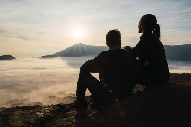 Couple enjoying sunrise at Mount Bromo volcano with scenic misty landscape model released, Symbolfoto, PNAF06817