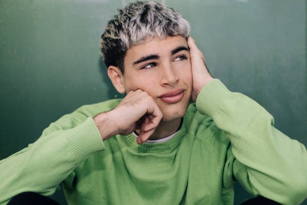 Thoughtful young man resting outdoors with head on hand in green sweater model released, Symbolfoto, STIF00009
