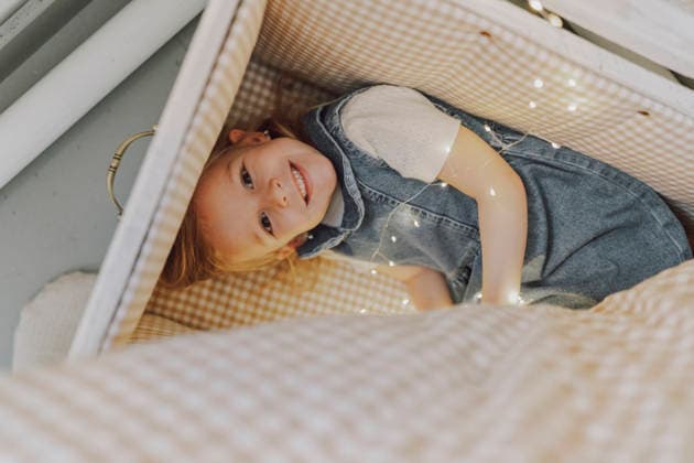 Happy child sitting in a cozy box with fairy lights indoors model released, Symbolfoto property released, VBUF00733