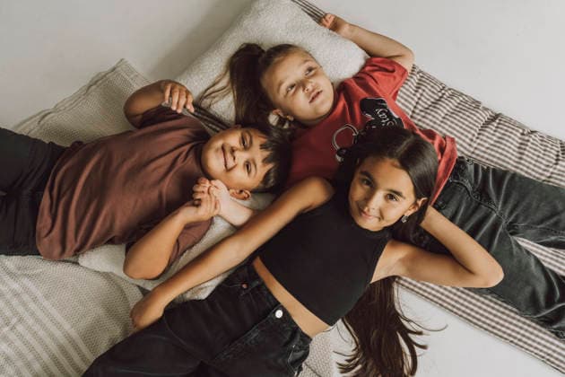 Happy siblings lying together enjoying time at home on mattress model released, Symbolfoto property released, VBUF00756