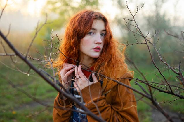 Red-haired woman in orange hoodie and denim overall in foggy forest model released, Symbolfoto, VCF01242
