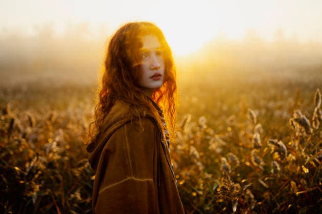 Woman with red hair in orange hoodie standing in sunny foggy field model released, Symbolfoto, VCF01250
