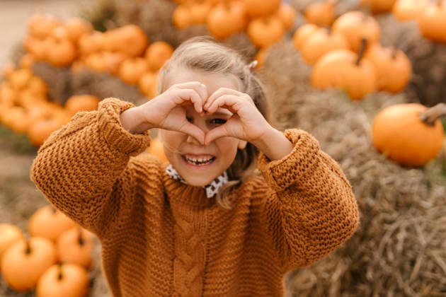 Child making heart gesture in pumpkin patch during autumn harvest model released, Symbolfoto, VIVF01728