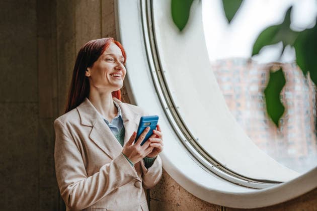 Businesswoman in formal wear using smartphone by office window model released, Symbolfoto property released, YTF04570