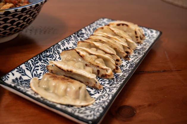 IMAGO Creative, Food, Dumplings Gebratene Teigtaschen auf dekorativem Servierteller 18.02.26, Eisenbach: Symbolfoto, Illustrationsbild, Symbolbild, Illustrationsfoto, Alltagsszene Nahaufnahme von gebratenen Teigtaschen, angerichtet auf einem rechteckigen Servierteller mit dekorativem Muster. Foodaufnahme auf einem Holztisch mit selektiver Schärfe und warmem Licht. Symbolbild für asiatische Küche, Fingerfood und kulinarische Vielfalt. Eisenbach Hessen Deutschland *** Fried dumplings on decorative serving plate 18 02 26, Eisenbach Symbol photo, illustration image, symbol image, illustration photo, everyday scene Close-up of fried dumplings, arranged on a rectangular serving plate with decorative pattern Food shot on a wooden table with selective sharpness and warm lig Copyright: xW2Artx xKlaraxMichelx