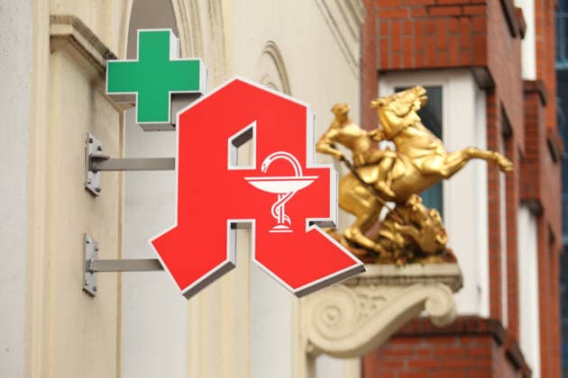 Ein Apotheken-A hängt an der Fassade einer Apotheke in der Langen Reihe. Dahinter ist eine Goldskulptur an die Fassade angebracht worden. St. Georg Hamburg *** A pharmacy A hangs on the facade of a pharmacy in Lange Reihe Behind it, a gold sculpture has been attached to the facade St Georg Hamburg