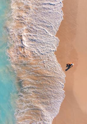 Aerial view of woman on sandy beach as ocean waves roll in. Grace Bay, Caicos Islands, Turks and Caicos Islands CR_DOHO260224B-1973403-01 ,model released, Symbolfoto