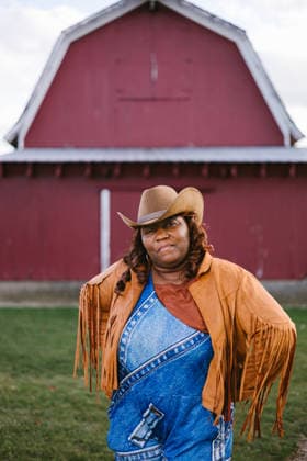 Black adult woman with cowboy hat, fringe jacket and red barn Gurnee, Illinois, United States CR_WVNP260219-1960124-01 ,model released, Symbolfoto