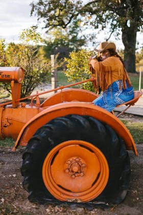 Black woman on orange tractor in cowboy hat and jacket Gurnee, Illinois, United States CR_WVNP260219-1960149-01 ,model released, Symbolfoto