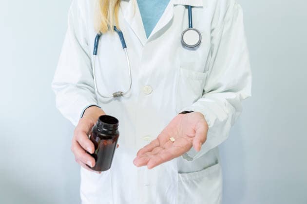Female doctor holding pills in medical office Cropped unrecognizable female doctor in a white coat holding a pharmaceutical bottle and dispensing pills into her hand, illustrating healthcare and medical practices in the office. Model Released GemaAlejo_ID33172_1129482_004 Copyright: xGemaxAlejox RECORD DATE NOT STATED