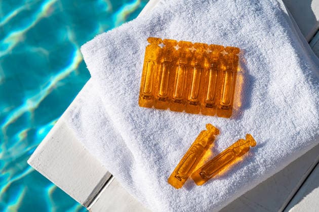 Hair care oil ampoules on a towel by the pool Orange hair care oil ampoules placed on a white towel beside a shimmering pool. Ideal for smoothness and sun protection, enhancing beauty and hair health. Model Released IrinaChetverikova_ID33524_1167070_002 Copyright: xIrinaxChetverikovax RECORD DATE NOT STATED
