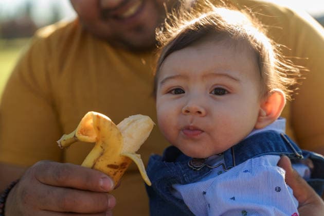 Father and child enjoying outdoor snack time together A warm moment capturing a Chilean father feeding his baby a banana outdoors. The sunlit scene highlights the bond and joy shared during this simple family activity. Model Released LuisABarrera_ID32997_1123608_001 Copyright: xLuisxAxBarrerax RECORD DATE NOT STATED