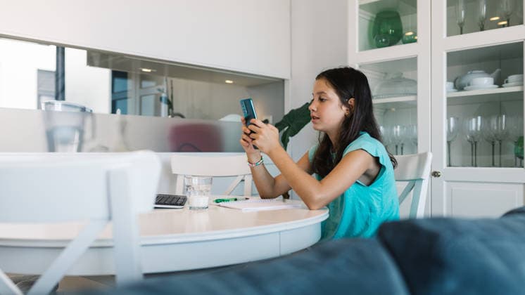 Girl studying at home with smartphone in hand Young girl engrossed in her homework, holding a smartphone while sitting at a table in a modern home setting, showcasing the blend of technology and education. Model Released SergioVictorVega_ID32572_1109821_010 Copyright: xSergioxVictorxVegax RECORD DATE NOT STATED