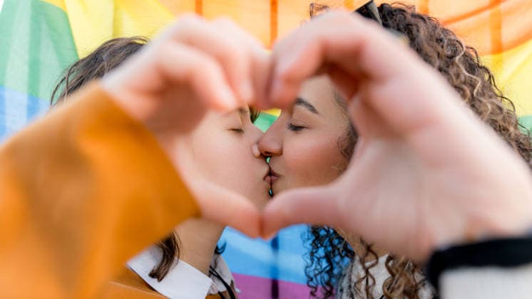 Young lesbians celebrating pride and love together Young lesbian couple sharing a tender kiss, framed by a heart shape made with hands, in front of a vibrant rainbow flag celebrating Pride and the LGBT community. Model Released SilviaRedondo_ID33866_1192357_015 Copyright: xSilviaxRedondox RECORD DATE NOT STATED