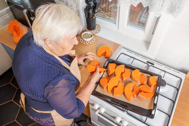 Woman preparing pumpkin for baking in kitchen A woman in her home kitchen prepares fresh pumpkin slices for baking on a tray. The cozy setting and natural light enhance the vibrant orange hues of the pumpkin pieces. Model Released SvetlanaRadayeva_ID33948_1196291_008 Copyright: xSvetlanaxRadayevax RECORD DATE NOT STATED