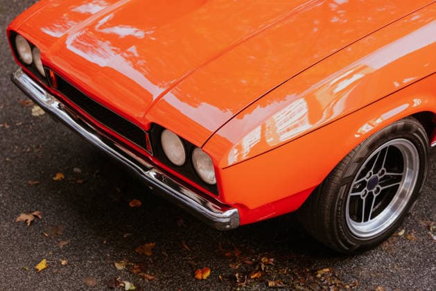 Vintage orange car with chrome details on street Close-up of a vintage orange car showing its shiny chrome details and classic design, parked on a leaf-covered street, capturing a nostalgic automotive atmosphere. Model Released VictorTorres_ID34247_1235938_041 Copyright: xVictorxTorresx