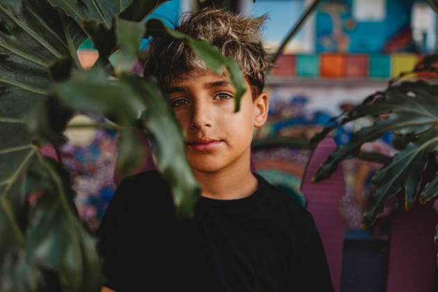 Serious boy standing behind a large green leaf. United States, California, San Diego CR_CHDO260218-1944903-01 ,model released, Symbolfoto