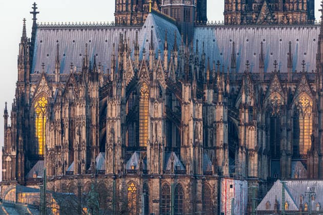 Sonnenaufgang in Köln. Detailaufnahme des Kölner Doms vom Deutzer Ufer aus. Die aufgehende Sonne spiegelt sich intensiv in einem der hohen gotischen Kirchenfenster der Kathedrale und taucht das Fenster in warmes Licht. Im Vordergrund sind Oberleitungen und Signalanlagen der Bahnstrecke unweit der Hohenzollernbrücke zu sehen. Köln Deutz Nordrhein-Westfalen Deutschland *** Sunrise in Cologne Close-up of Cologne Cathedral from Deutzer Ufer The rising sun is intensely reflected in one of the cathedrals tall Gothic stained glass windows, bathing the window in warm light The overhead lines and signaling systems of the railroad line can be seen in the foreground, not far from the Hohenzollern Bridge Cologne Deutz North Rhine-Westphalia Germany Copyright: xMarcxJohnx