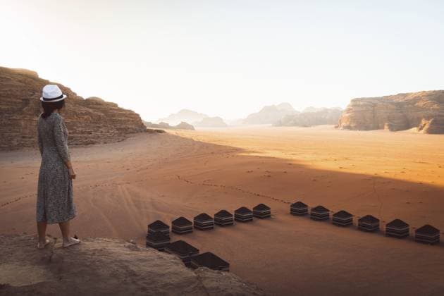 Kaukasische römische Touristen in Kleidung stehen auf einer Klippe am Aussichtspunkt bei Sonnenaufgang in der Wüste Wadi Rum und genießen das malerische Panorama der felsigen Landschaft. Jordanien: Erkunden Sie das Konzept Caucasian oman tourist in dress stand on cliff at viewpoint on sunrise in Wadi Rum desert enjoy scenic rocky landscape panorama. Jordan explore concept Copyright: imageBROKER EvaldasxMikoliunas ibxemi16791772.jpg ,model released, Symbolfoto ,property released