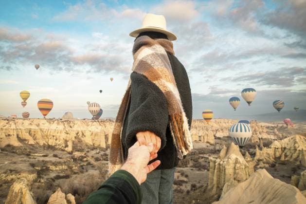 Paar halten Handshow und schauen aus, bewundern die Heißluftballonshow, tragen modische Kleidung, stellen Sie sich auf einen malerischen Aussichtspunkt, beobachten Sie die Heißluftballonfahrt bei Sonnenaufgang mit der schönen Stadt Göreme und dem Tal im Hintergrund Couple hold hand show looking admire hot air balloon show, wear fashionable clothing stand on scenic viewpoint watch hot air balloon flight on sunrise with beautiful goreme town and valley background Copyright: imageBROKER EvaldasxMikoliunas ibxemi16791988.jpg ,model released, Symbolfoto ,property released