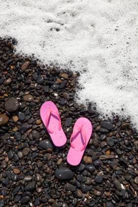 A pair of pink flip flops rest on wet rocks as a foamy ocean wave approaches the shore in Florence, Oregon. Footwear,United States,A pair of pink flip flops rest on wet rocks as a foamy ocean wave approaches the shore in Florence, Oregon.  A pair of pink flip flops rest on wet rocks as a foamy ocean wave approaches the shore in Florence, Oregon.