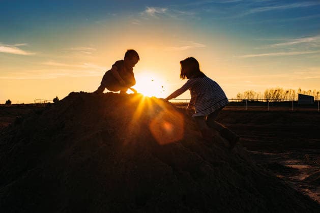 Two Children climbing on Dirt pile at Sunset Tulsa, Oklahoma, United States CR_KRRY260307-1977848-01 ,model released, Symbolfoto