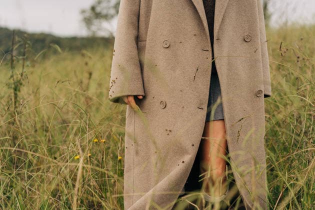 Nahaufnahme eines übergroßen beigen Mantels, den eine nicht erkennbare Frau trägt, die auf einer wilden Wiese steht. Close-up of an oversized beige coat on an unrecognizable woman standing in a wild meadow. (License=RF) ,model released, Symbolfoto Copyright: xZoonar.com TITOVAxILONAx 24760398 ,model released, Symbolfoto ,property released