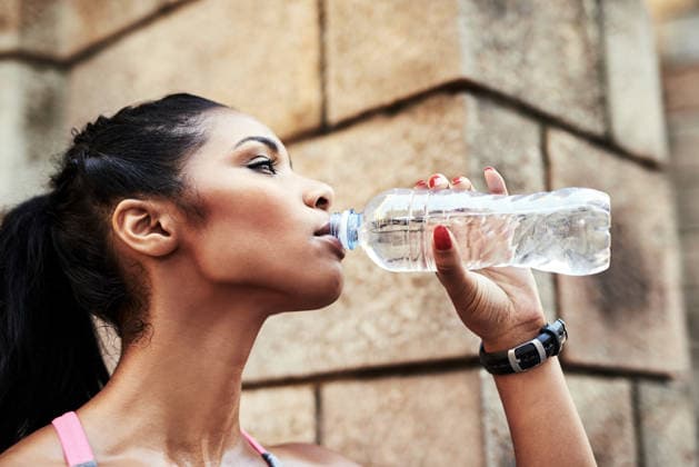 Woman, drinking water and fitness in city with training, rest and hydration for wellness in morning. Person, runner and bottle for liquid, detox or gut health on break for exercise in urban town. model released property released Copyright: xx