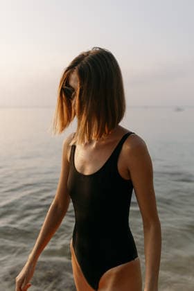 Woman in black swimsuit standing in calm sea at sunrise Koh Samui, Surat Thani, Thailand CR_RXIF260304B-1976419-01 ,model released, Symbolfoto