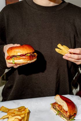 Girl holding a burger in her hands in a restaurant isolated Toru?, Kuyavian-Pomeranian Voivodeship, Poland R_ORVG260304-1967793-01