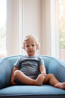 Portrait, girl and young child in daycare with couch, relax and curious for childhood development. Innocent, kid chill and toddler safe in creche with learning, growth or childlike wonder for future model released property released Copyright: xx