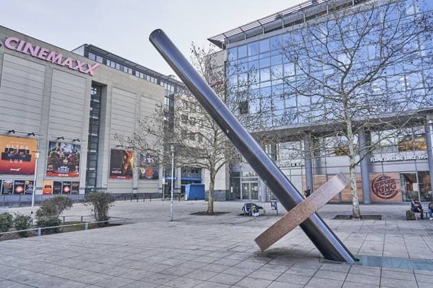 Die Erdachse in Magdeburg ist ein bekanntes Kunstobjekt des Künstlers Timm Ulrichs, das 1999 auf dem Willy-Brandt-Platz vor dem Hauptbahnhof und dem City Carré installiert wurde. Sie ist eine künstlerische Interpretation der Erdachse und dient als Ort der Standortbestimmung, Skulptur in einer Fußgängerzone vor einem Kinogebäude mit Plakaten und Bäumen, Straßenkunst, Polsprung, Erdpole, Erdhalbkugel, Neigung der Erde, Erdrotation, Jahreszeiten The Earth s Axis in Magdeburg is a well-known art object by artist Timm Ulrichs, which was installed in 1999 on Willy-Brandt-Platz in front of the main train station and the City Carré. It is an artistic interpretation of the Earth s axis and serves as a location, sculpture in a pedestrian zone in Copyright: imageBROKER streetxnews iblbee17001945.jpg