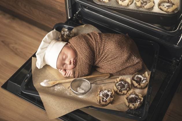 Süßes Neugeborenes mit Kochmütze liegt mit Muffins auf dem Backblech Cute newborn baby wearing chef s hat is lying on the oven tray with a muffins Copyright: imageBROKER blackday ibxiqx16980013.jpg ,model released, Symbolfoto ,property released