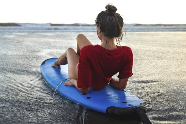 Junge Frau sitzt nach ihrer Surf Session auf einem Surfbrett am Strand Young woman sitting on surfboard on the beach after her surfing session Copyright: imageBROKER blackday ibxiqx16981659.jpg ,model released, Symbolfoto ,property released